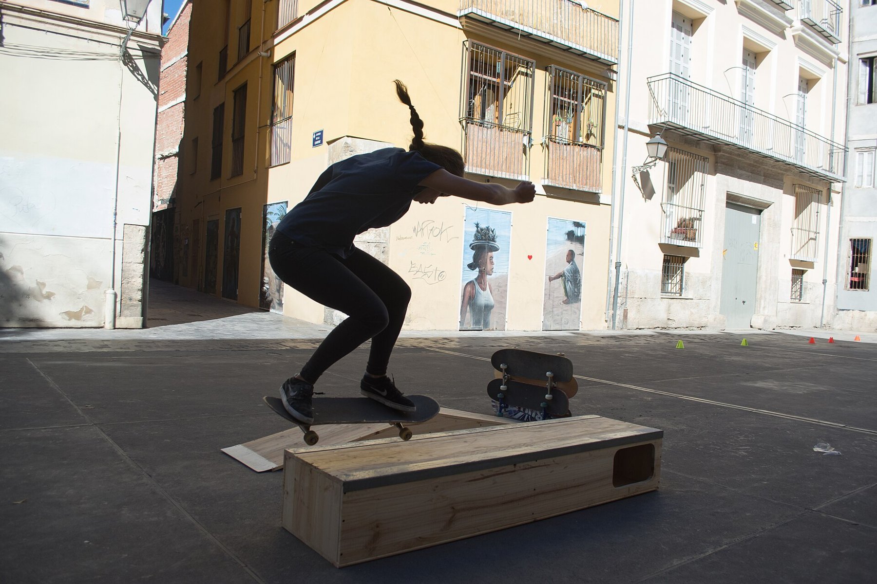 Skaterin springt mit ihrem Board vor einer historischen Säule in Valencia