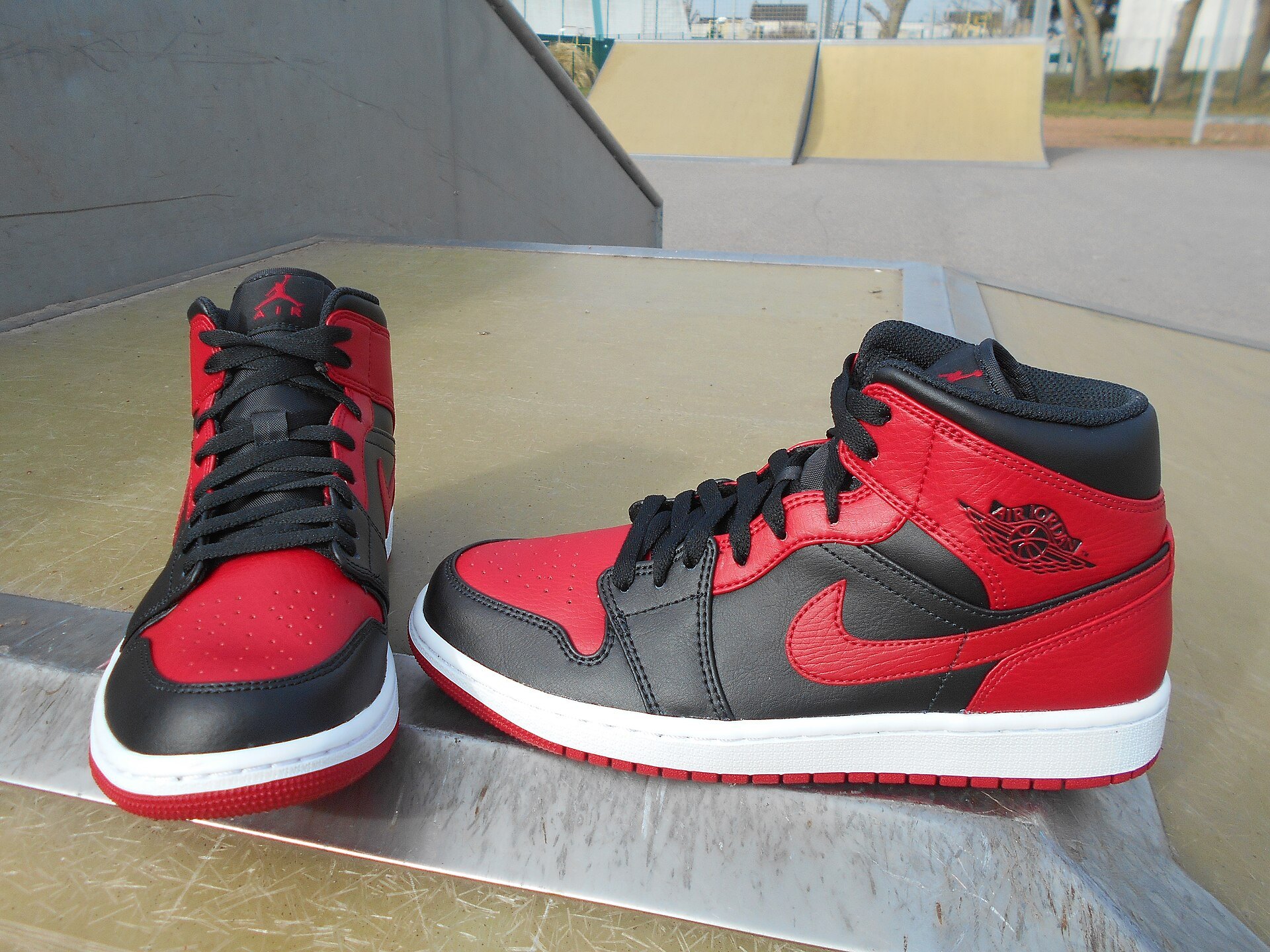 Air Jordan 1 Mid in Schwarz-Rot aus dem Jahr 2020 auf einer Skatepark-Rampe