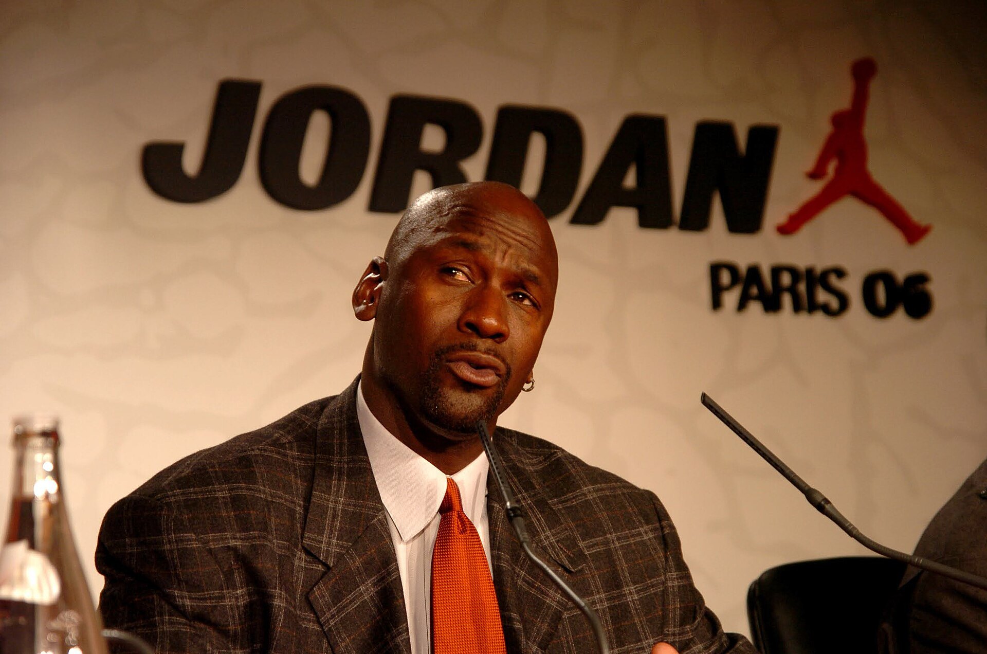 Michael Jordan im Anzug bei einer Pressekonferenz vor dem Jordan-Schriftzug mit Jumpman-Logo in Paris 2006