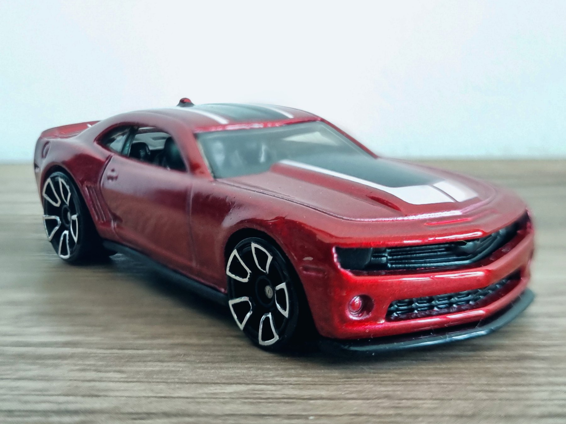 Rotes Hot-Wheels-Modell eines Chevrolet Camaro aus der Mainline 2013 mit Kunststoffrädern auf einem Holztisch