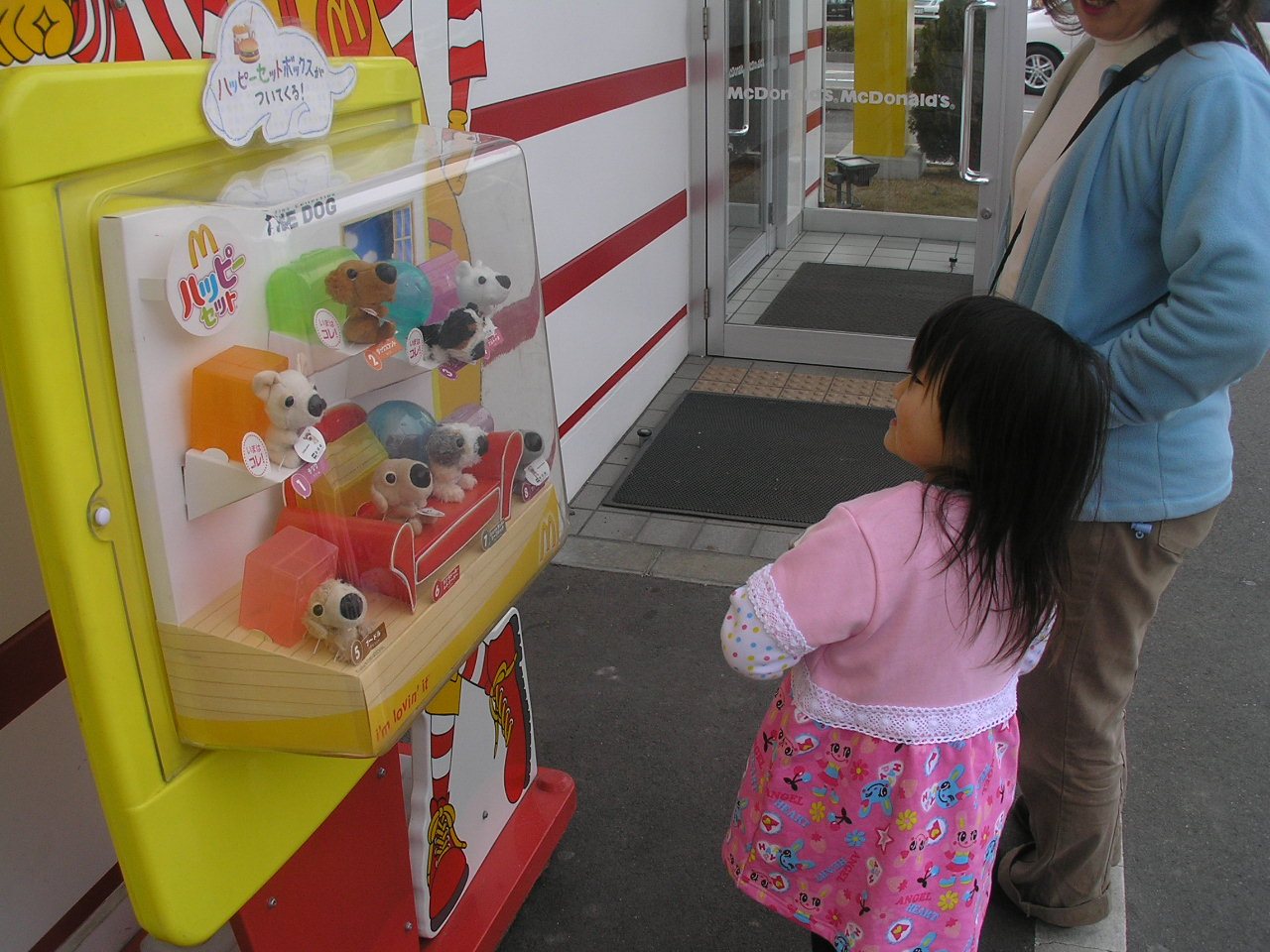 Kind betrachtet eine Schauvitrine mit Happy-Meal-Spielzeugfiguren vor einem McDonald’s in Japan, 2005
