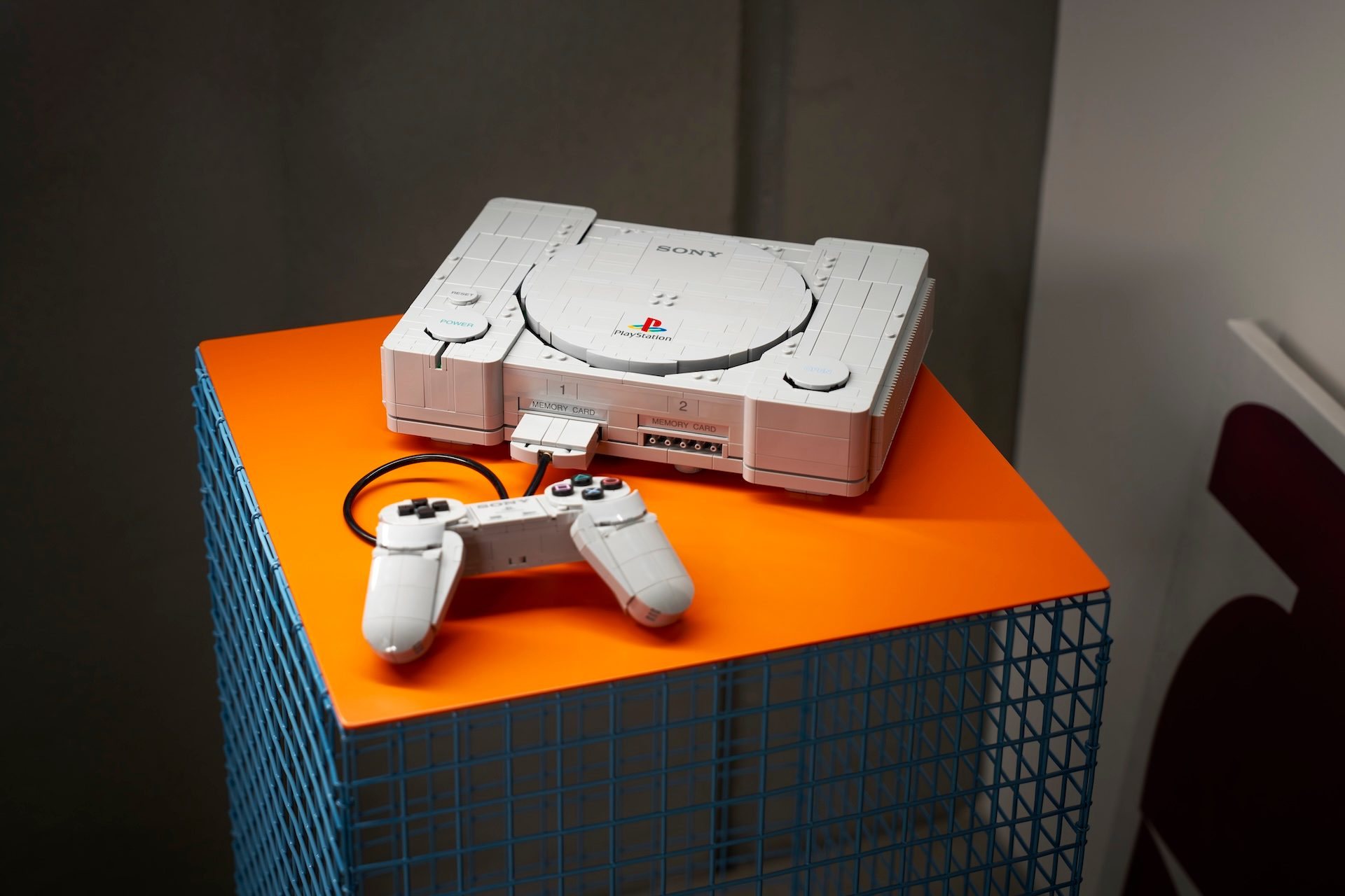 LEGO PlayStation 72306 mit Controller als Displaymodell auf einem orangefarbenen Sockel