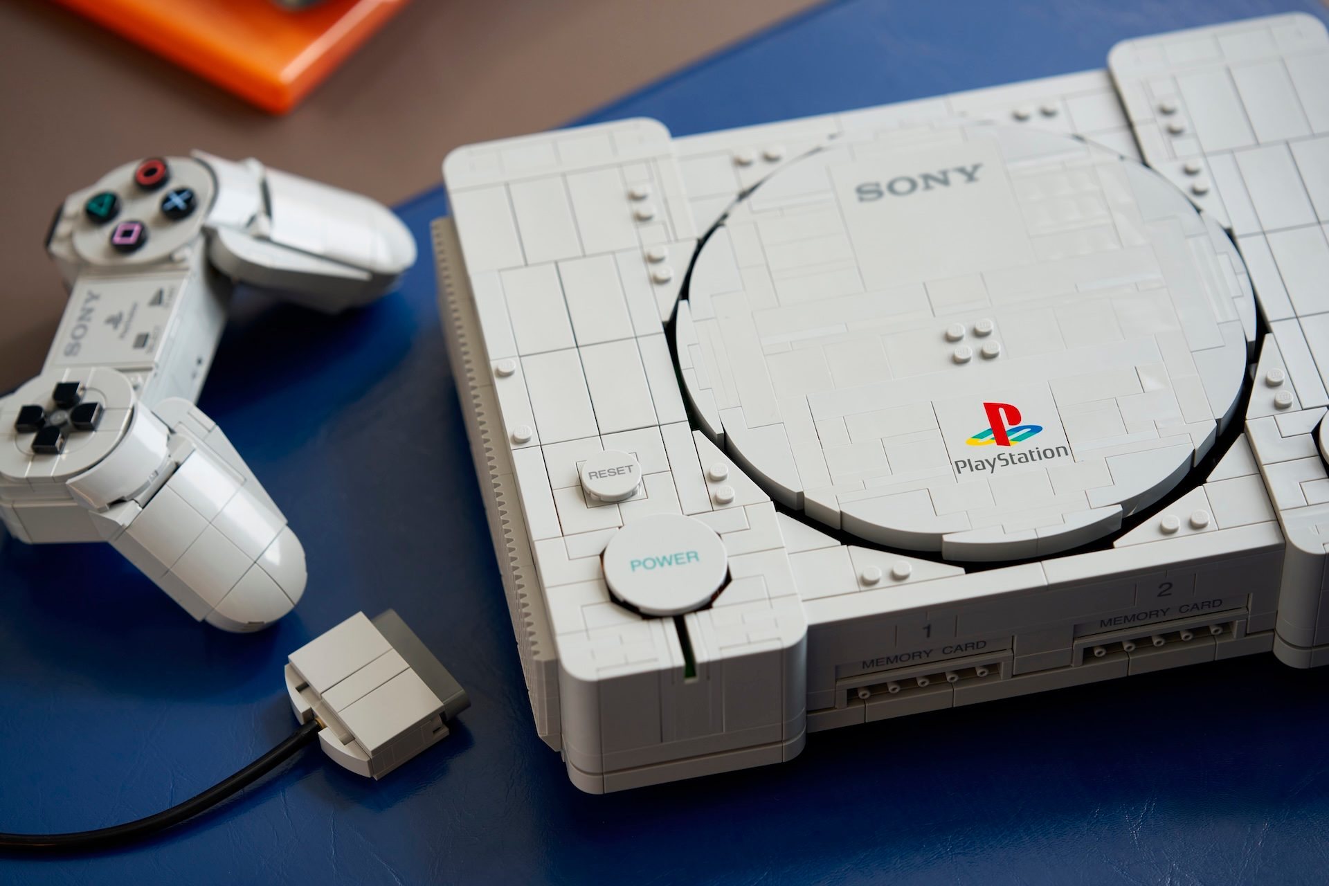 LEGO PlayStation 72306 mit grauer Konsole und angeschlossenem LEGO Controller auf blauem Untergrund